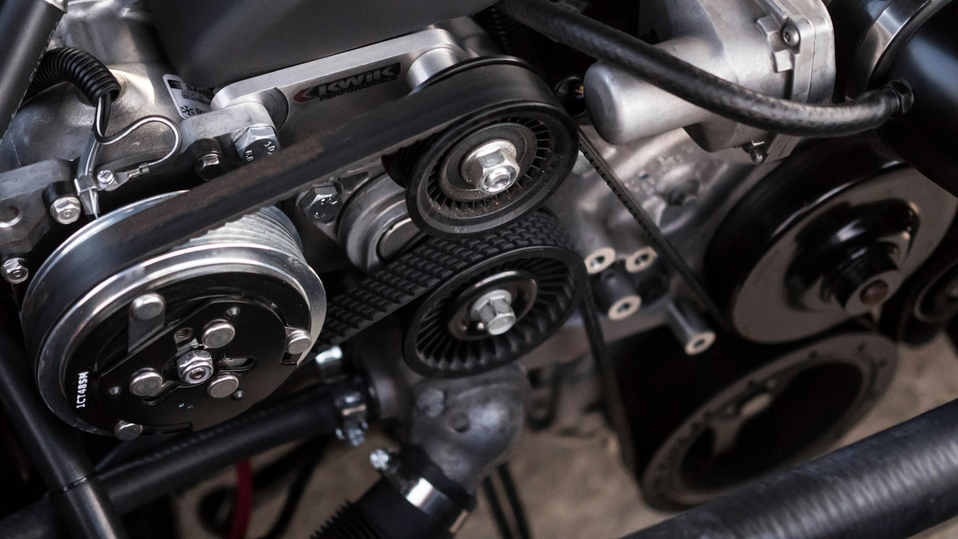 Mechanic in a dark workshop examining a vehicle engine under focused light